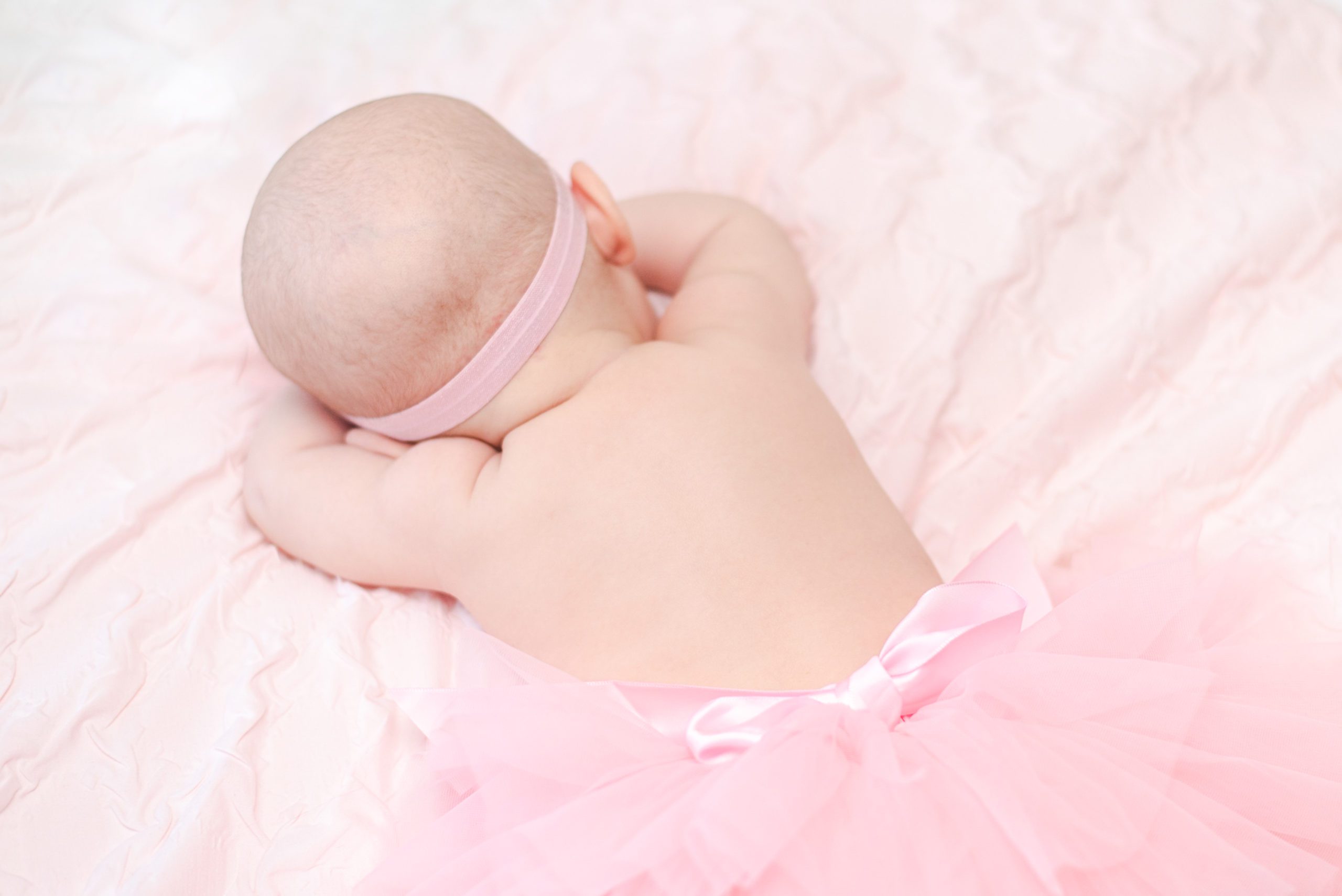 Annessa wearing a pink tutu and laying on the bed