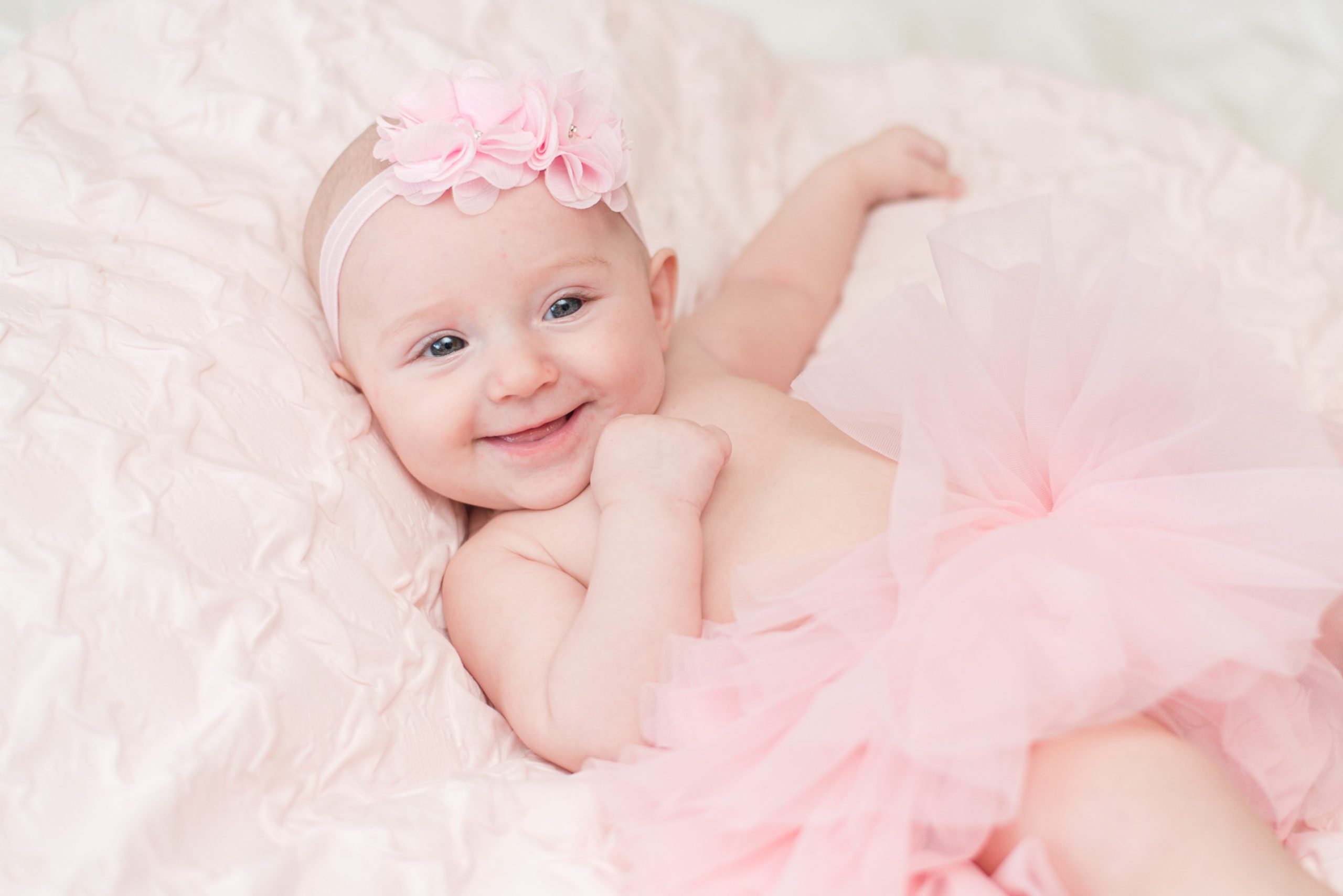 Annessa at 3 months smiling and wearing a pink tutu