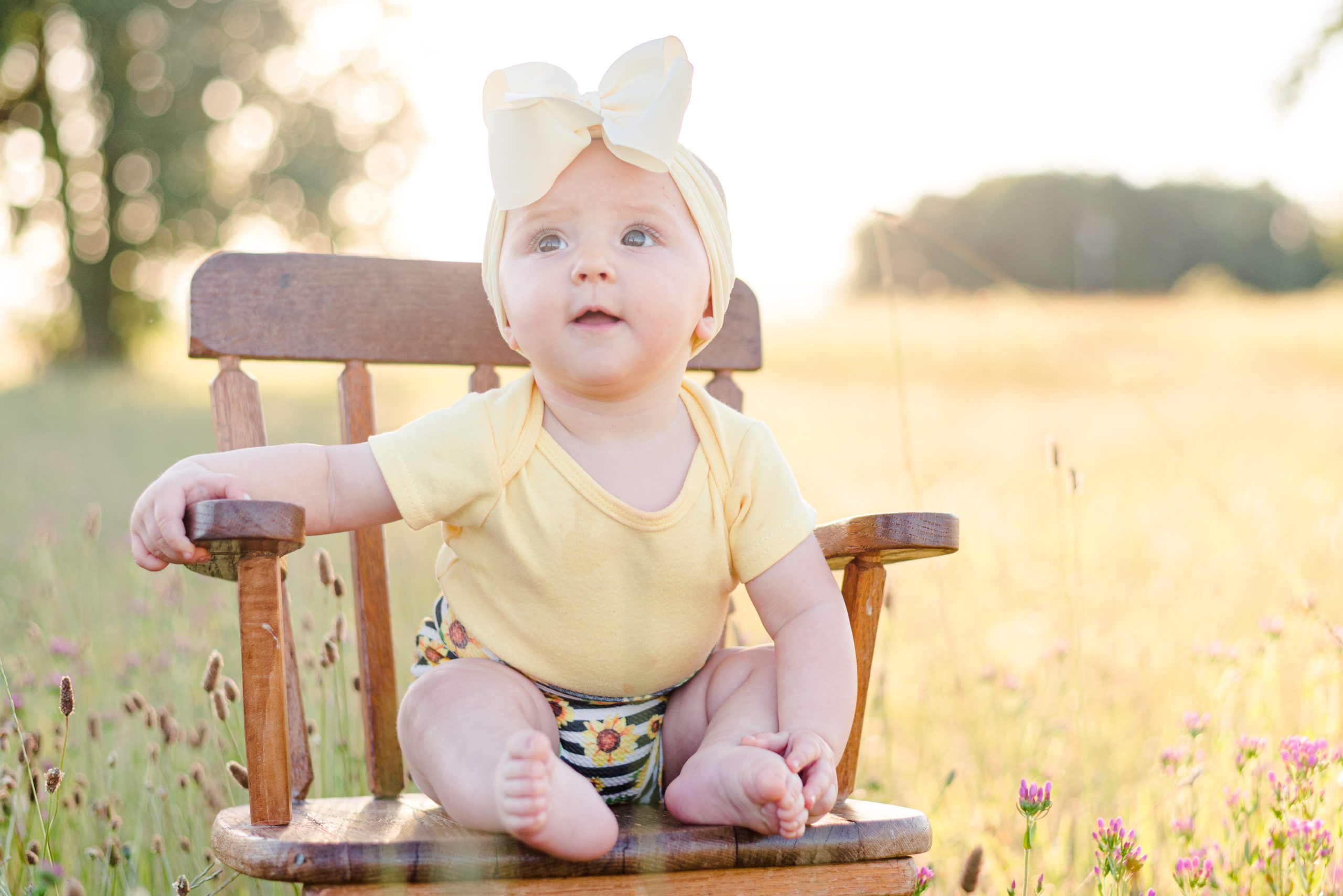 6 month old Annessa sitting in a rocking chair in a field at sunset