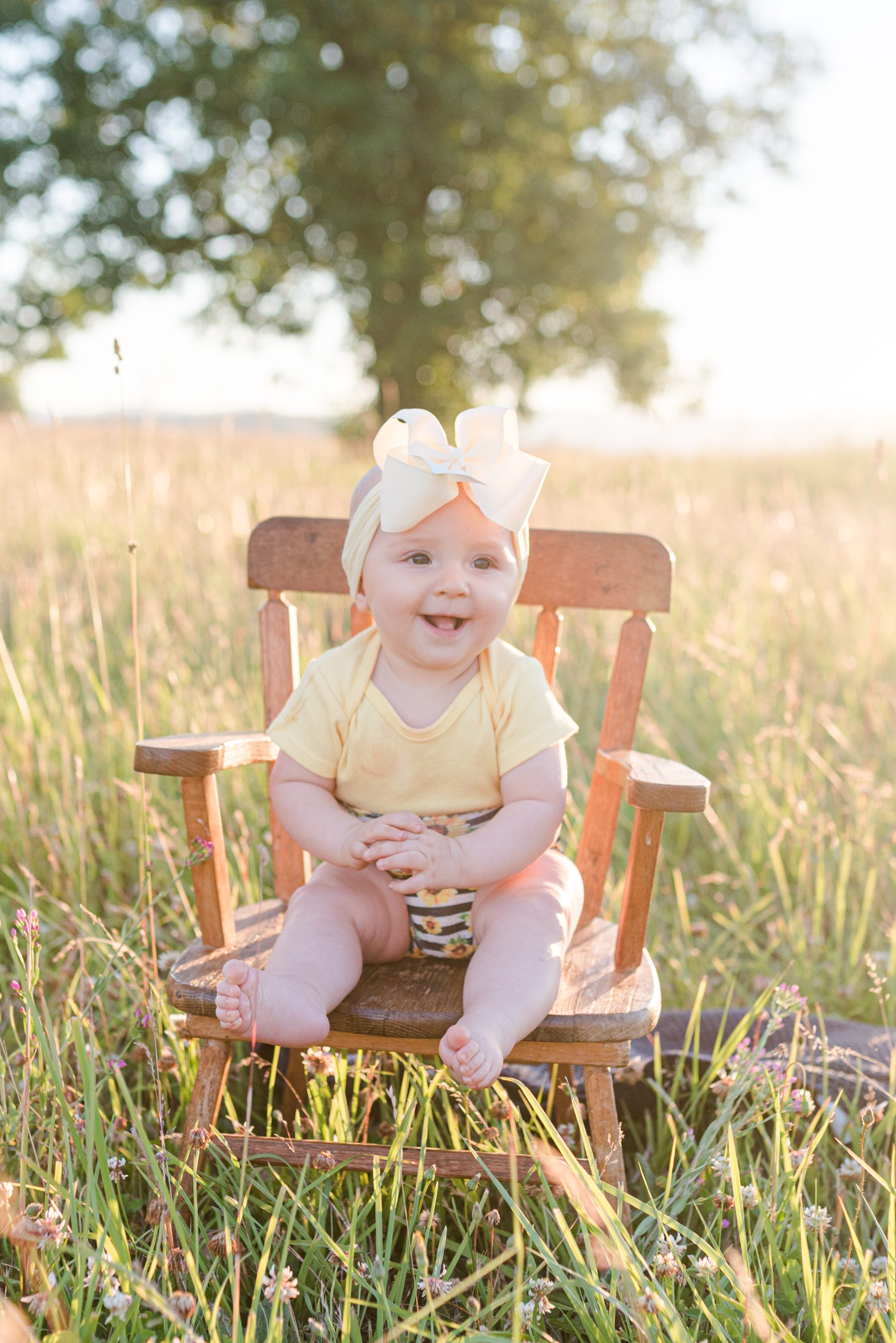 6 month old Annessa sitting in a rocking chair in a field at sunset