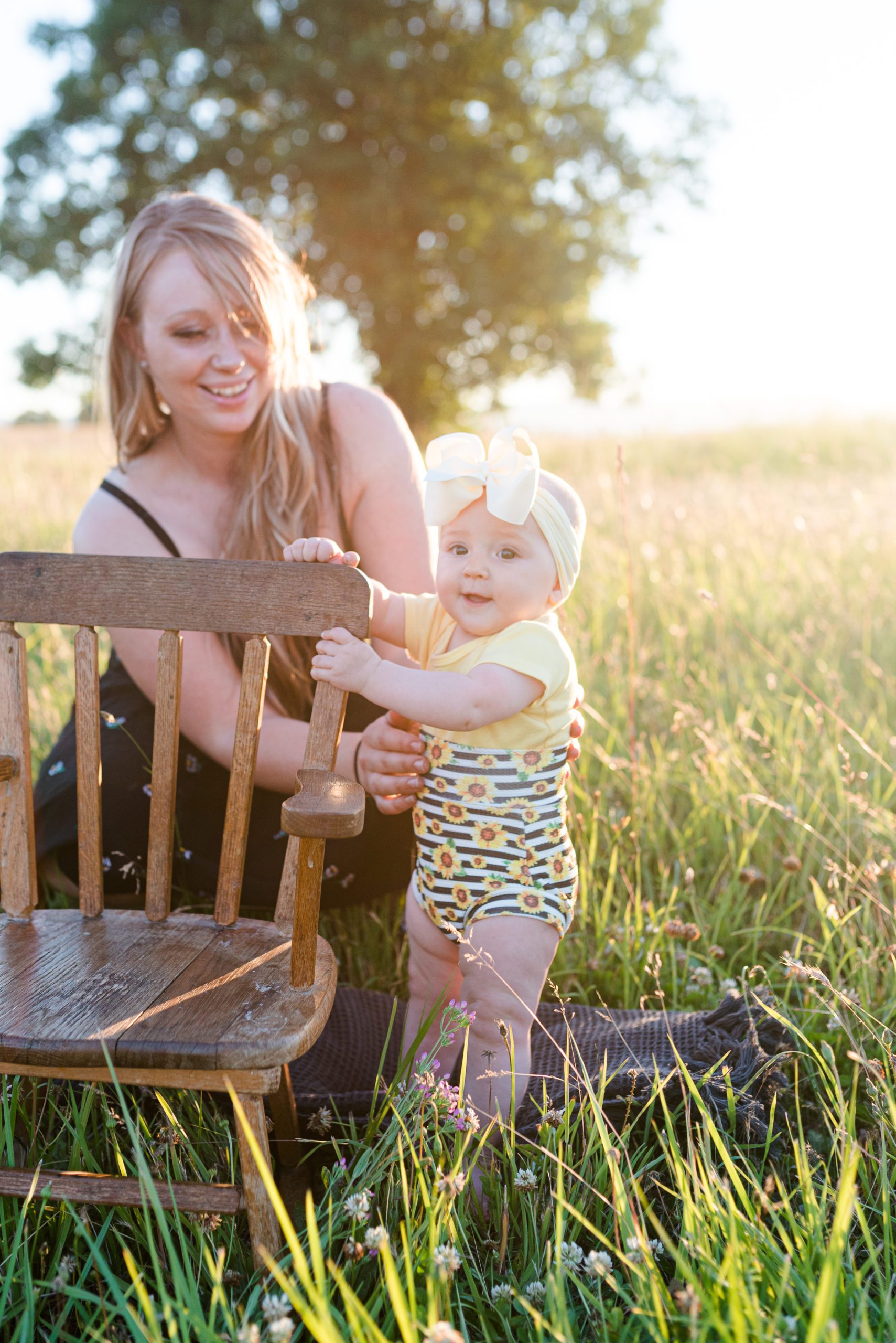 6 month old Annessa sitting in a rocking chair in a field at sunset with her mom