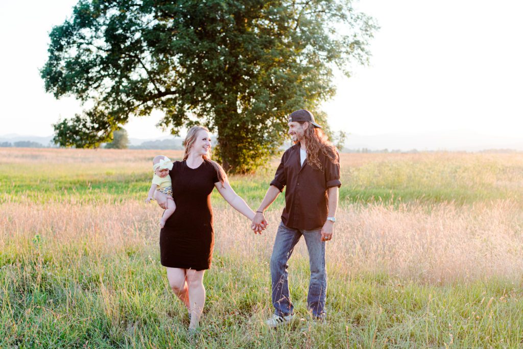 6 month old Annessa with her parents in a field at sunset