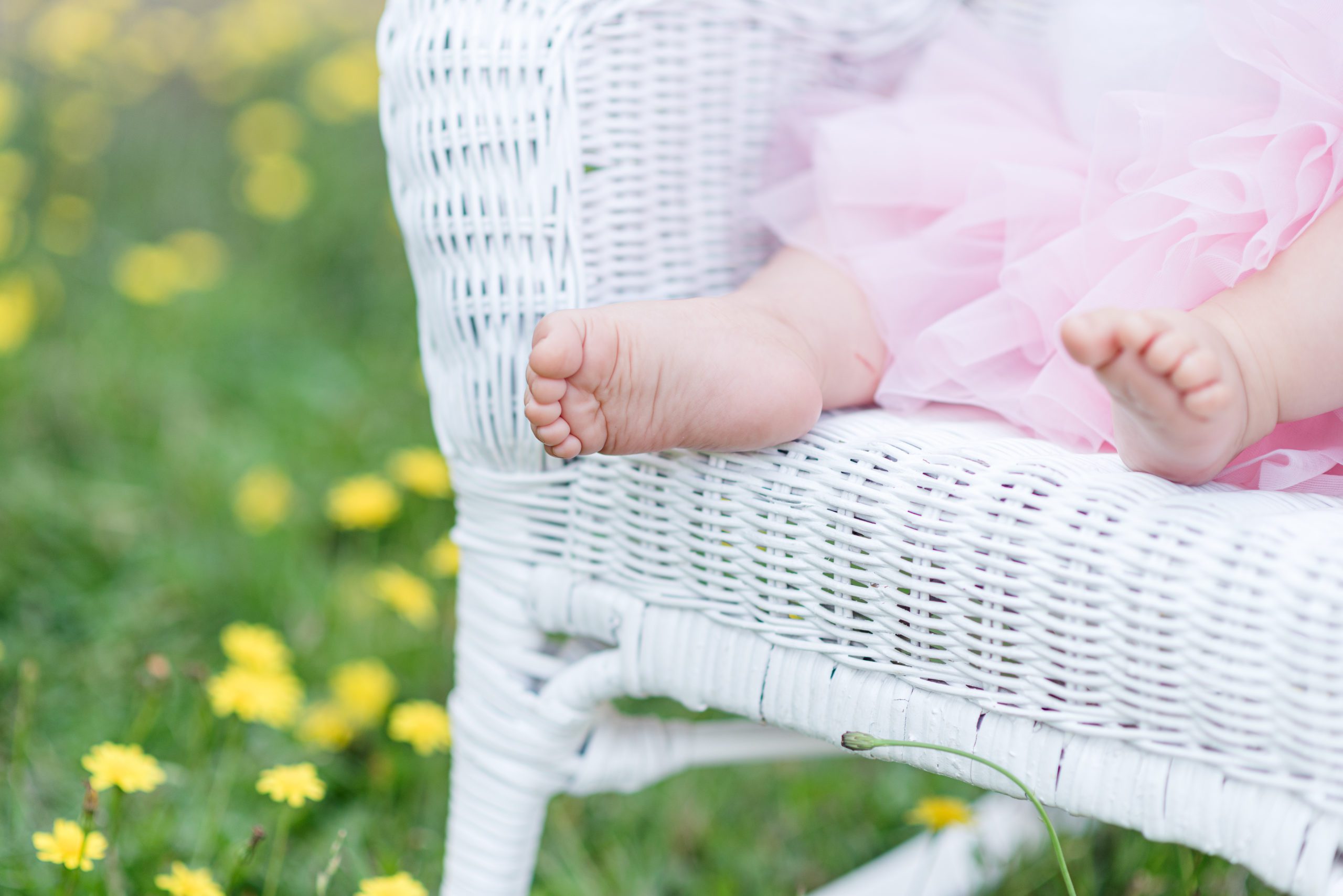 Annessa's toes at 9 months sitting in a white rocking chair in a field