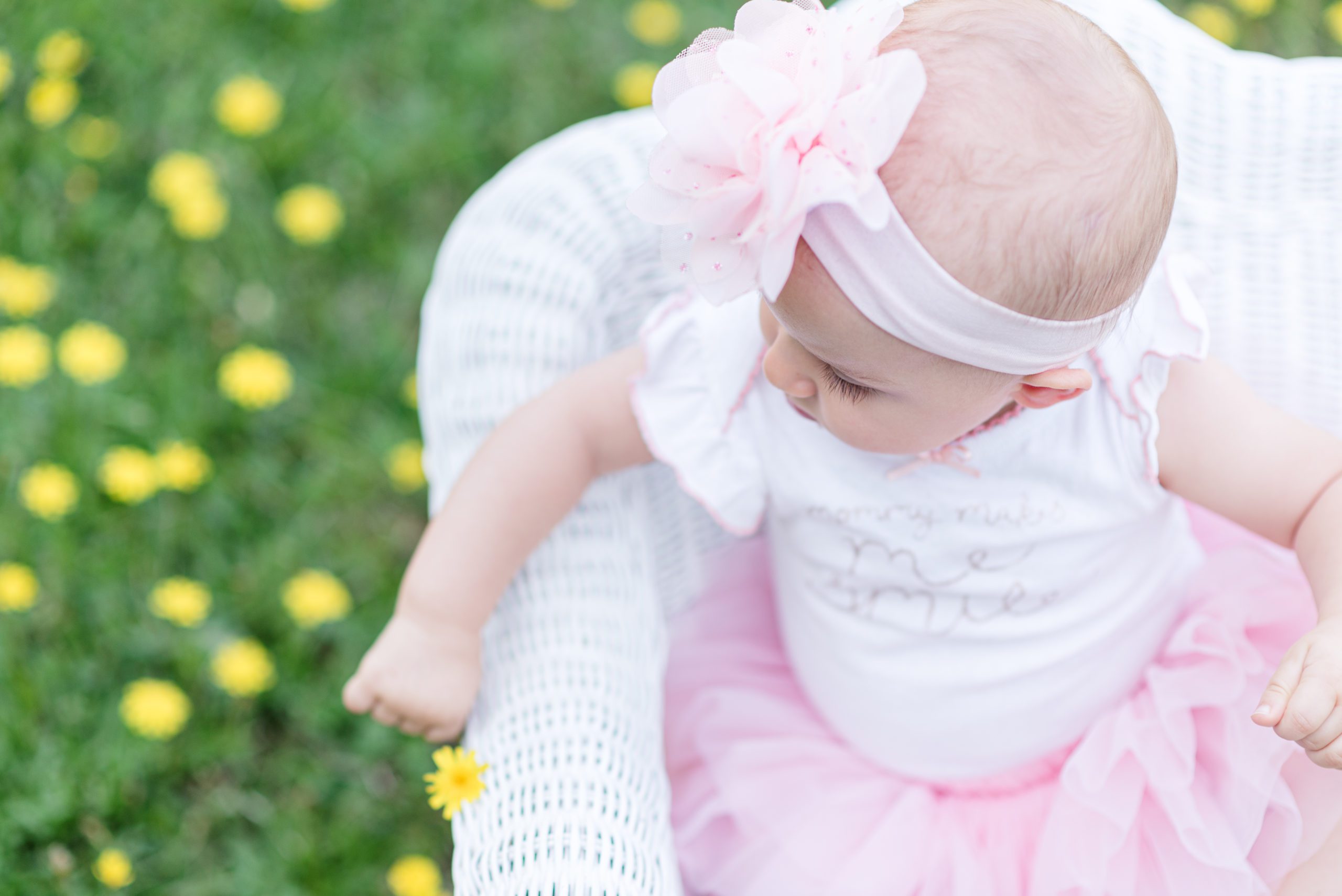 Annessa at 9 months sitting in a white rocking chair in a field