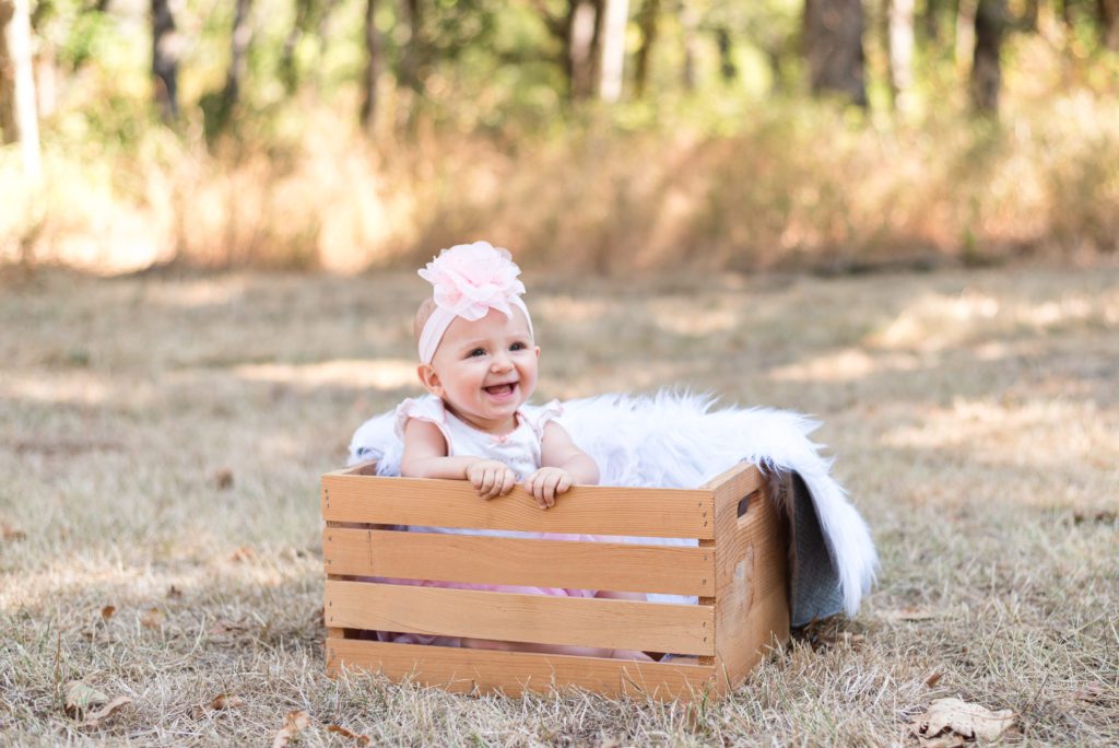 Annessa at 9 months sitting in a crate in a field