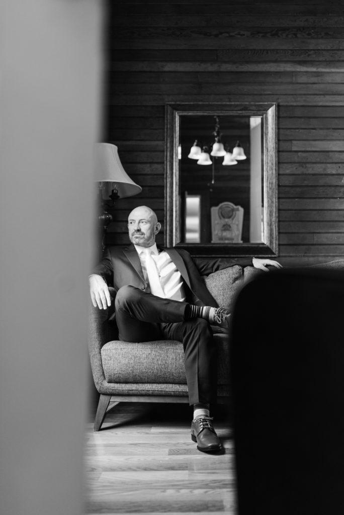 Groom sitting on couch looking out window