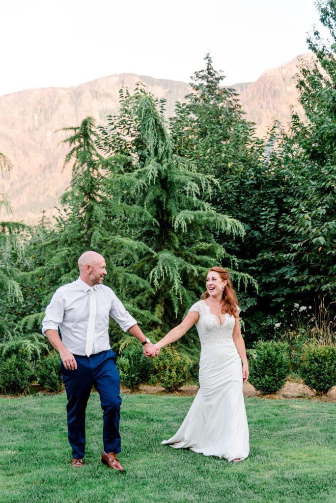 Couple walking in grass holding hands at Cape Horn Estate