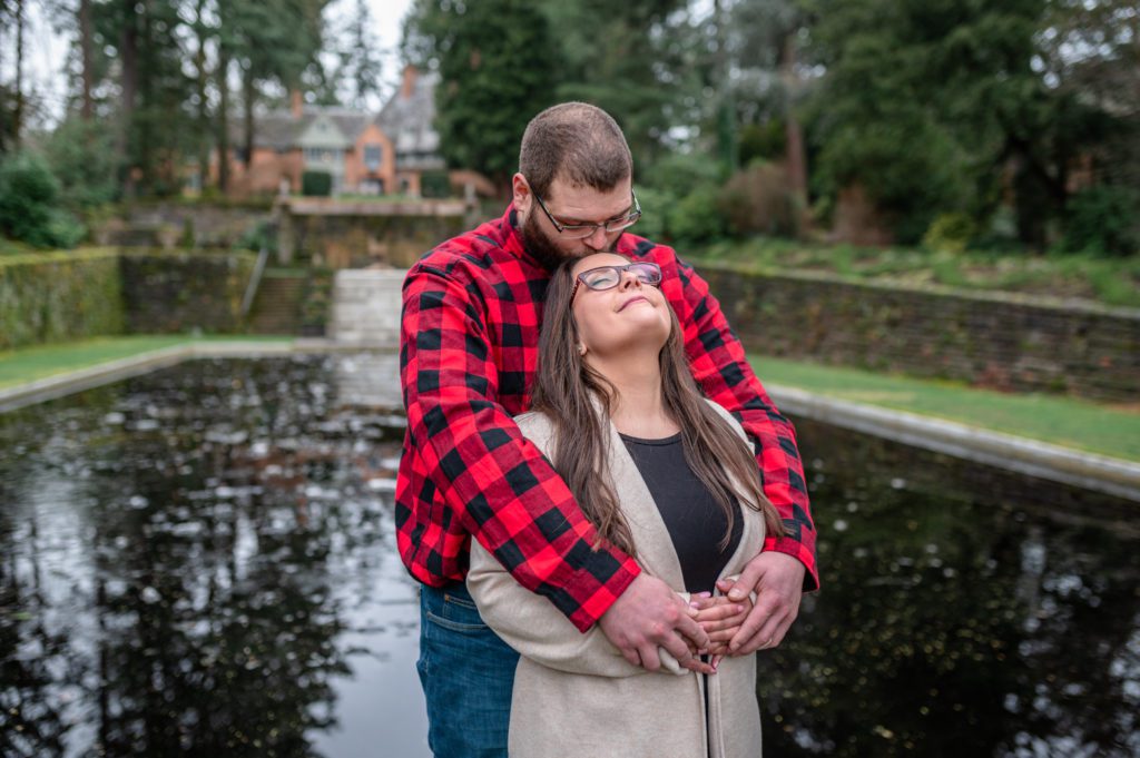 Kissing on forehead in front of reflecting pool at Lewis and Clark College