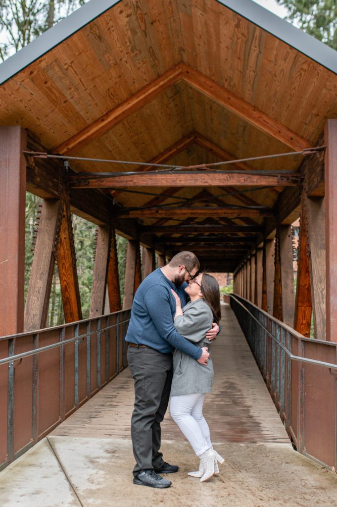 Engaged couple kissing under bridge at Lewis and Clark College