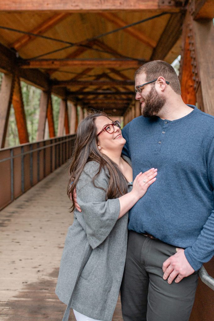 Engaged couple looking at each other under covered bridge