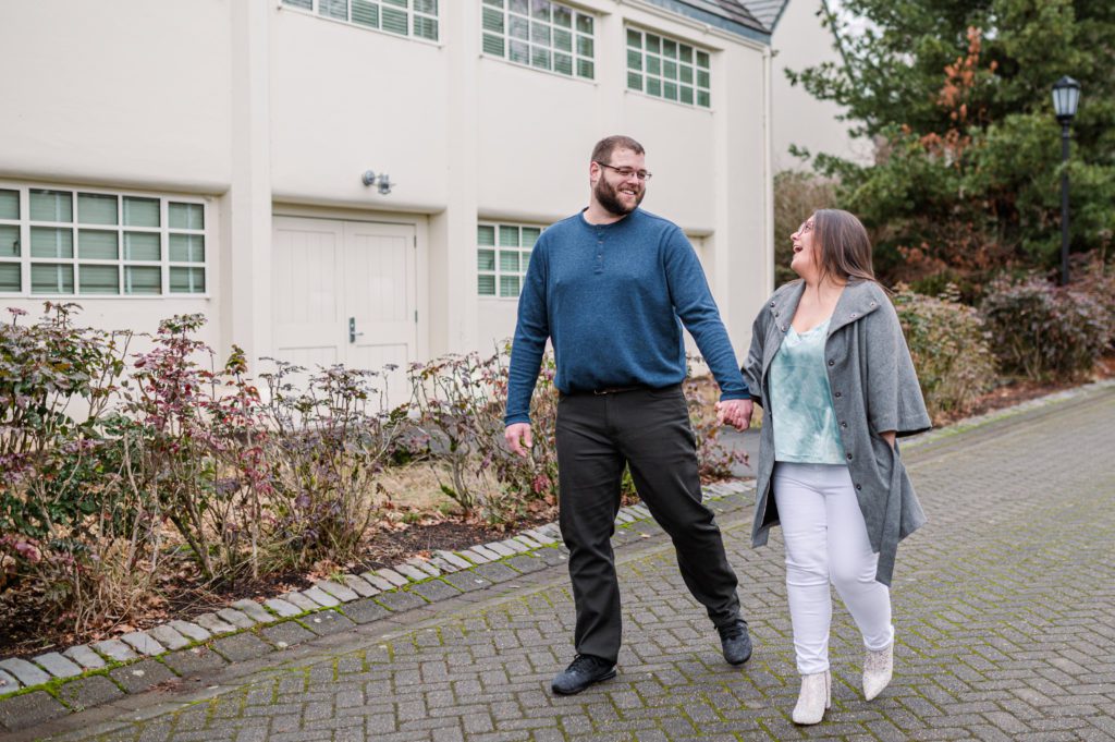 Engaged couple holding hands and walking while laughing