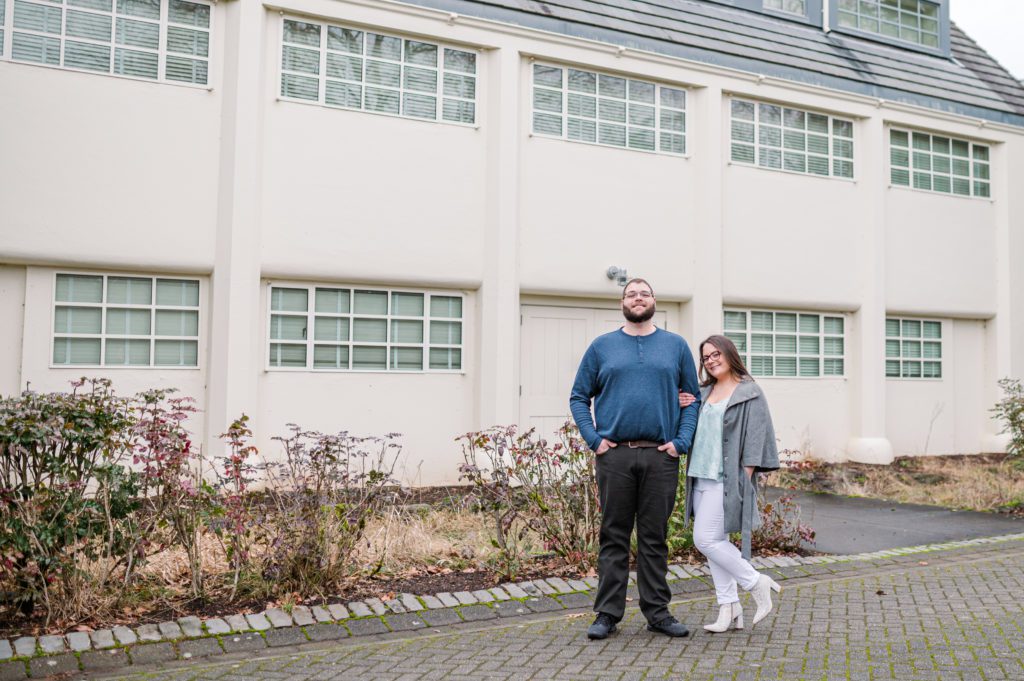 Engaged couple locking arms in front of building