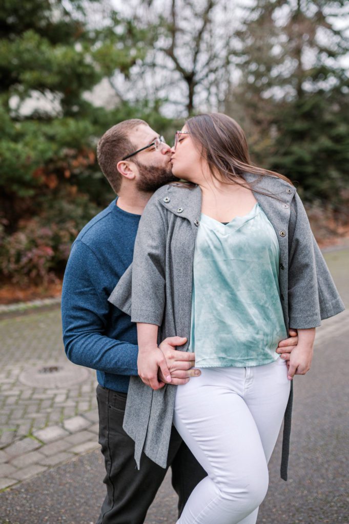 Engaged couple kissing on rock