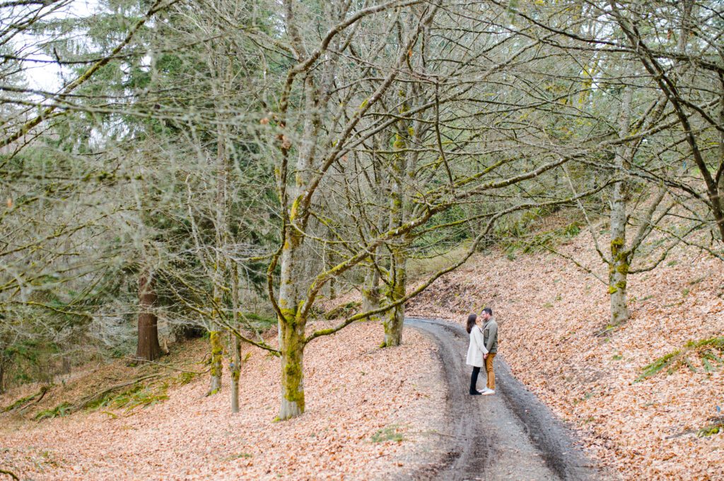Engaged couple walking down path with leaves