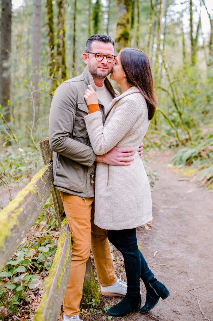 Engaged couple leaning on fence