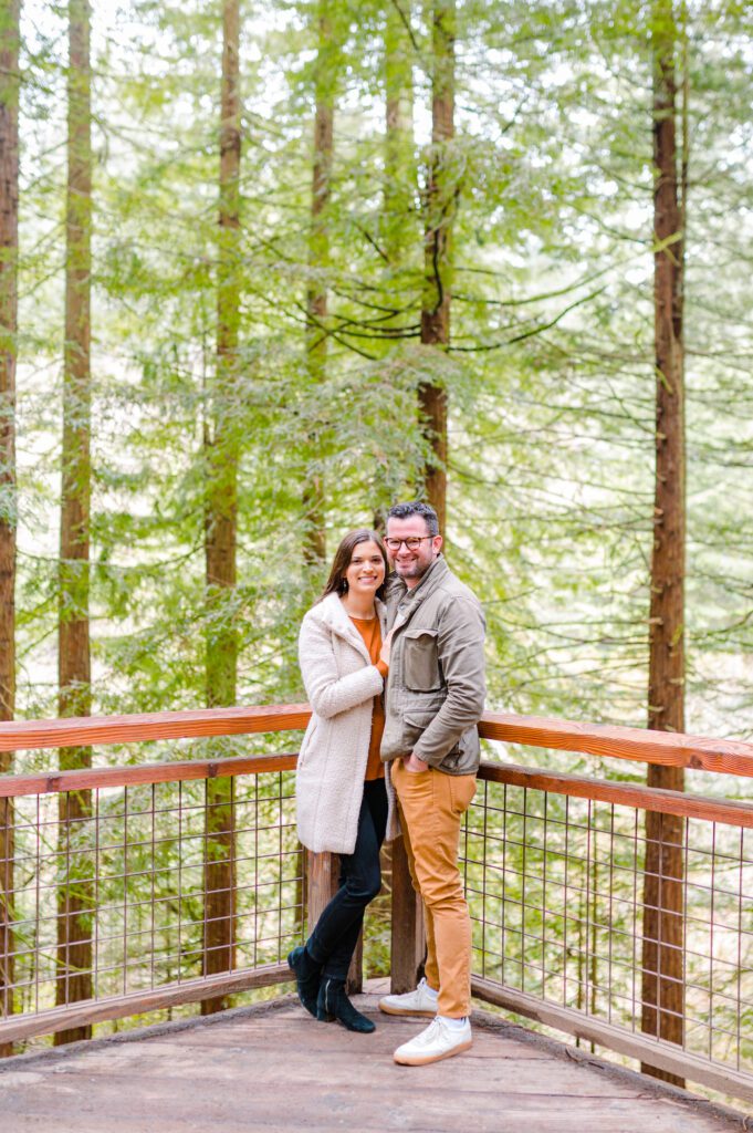 Engaged couple standning on deck in woods