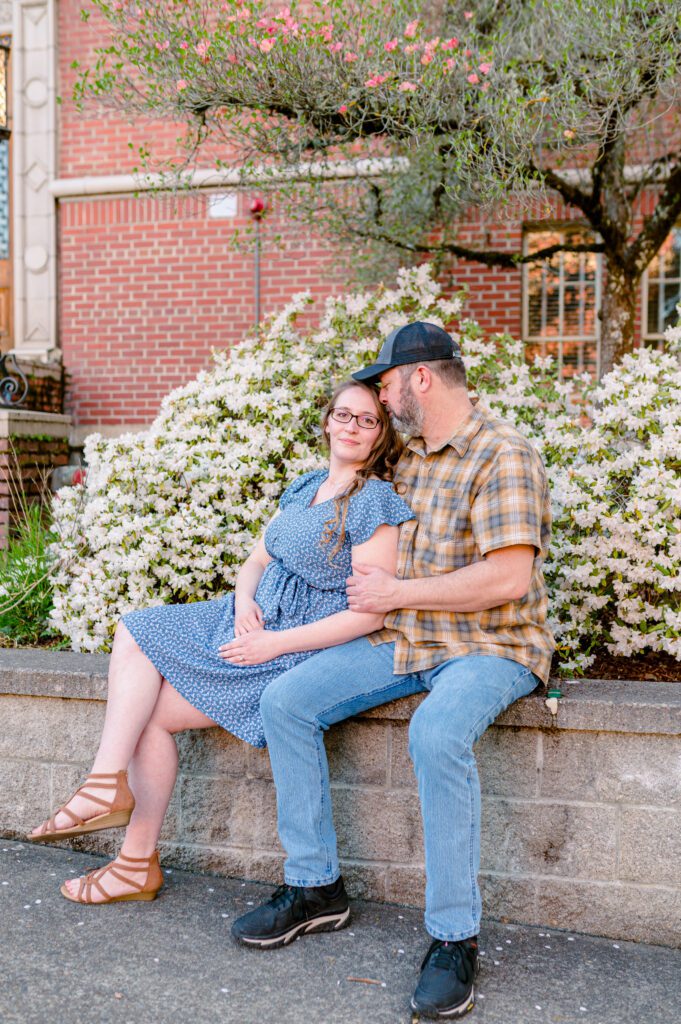 Engaged couple sitting in front of flowers