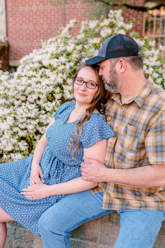 Engaged couple sitting in front of flowers