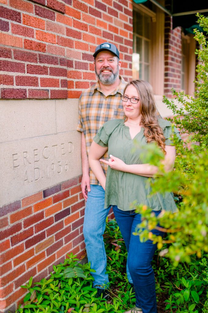 Engaged couple laughing and pointing at an erected in 1936 sign on building