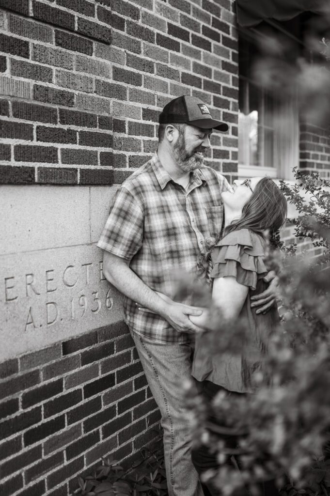 Engaged couple laughing and smiling at an erected in 1936 sign on building