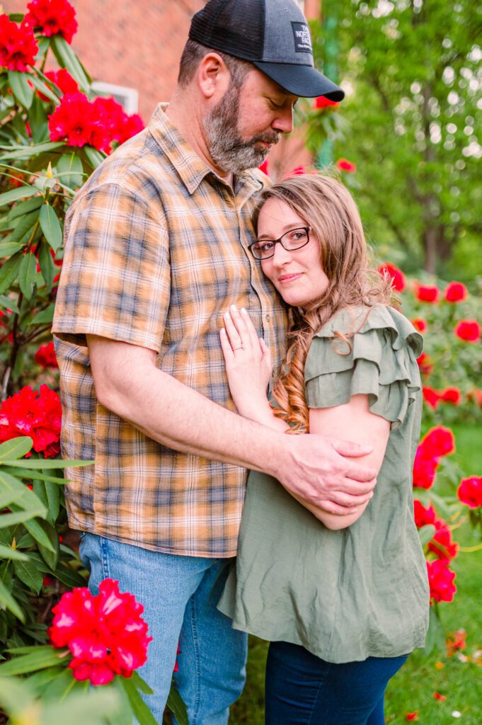 Bride to be looking at camera in the red flower bushes