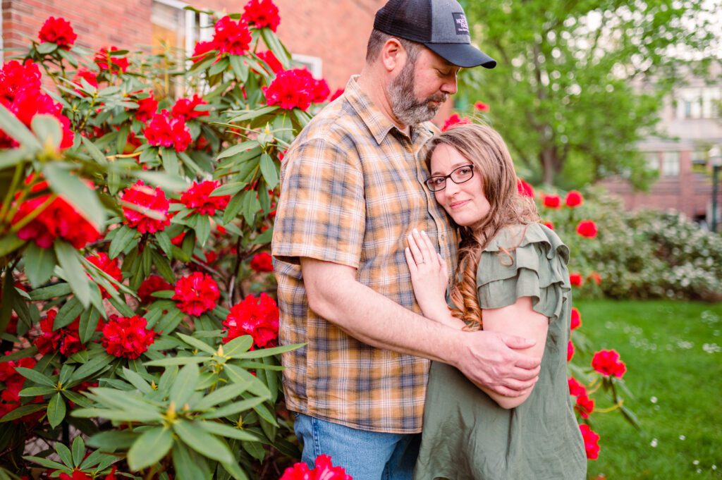 Bride to be looking at camera in the red flower bushes