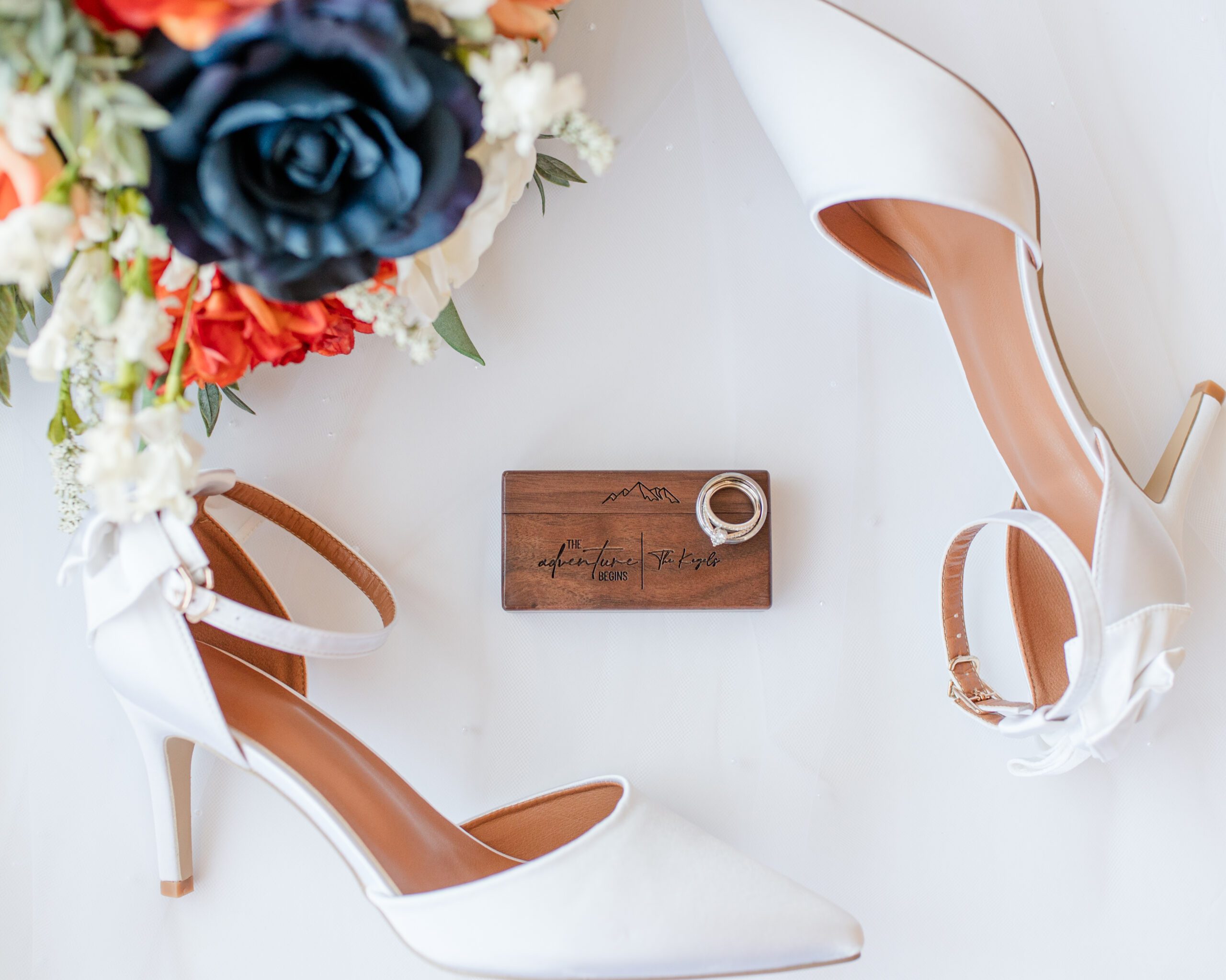 Bridal details of her white heals, shoes, ring box and rings