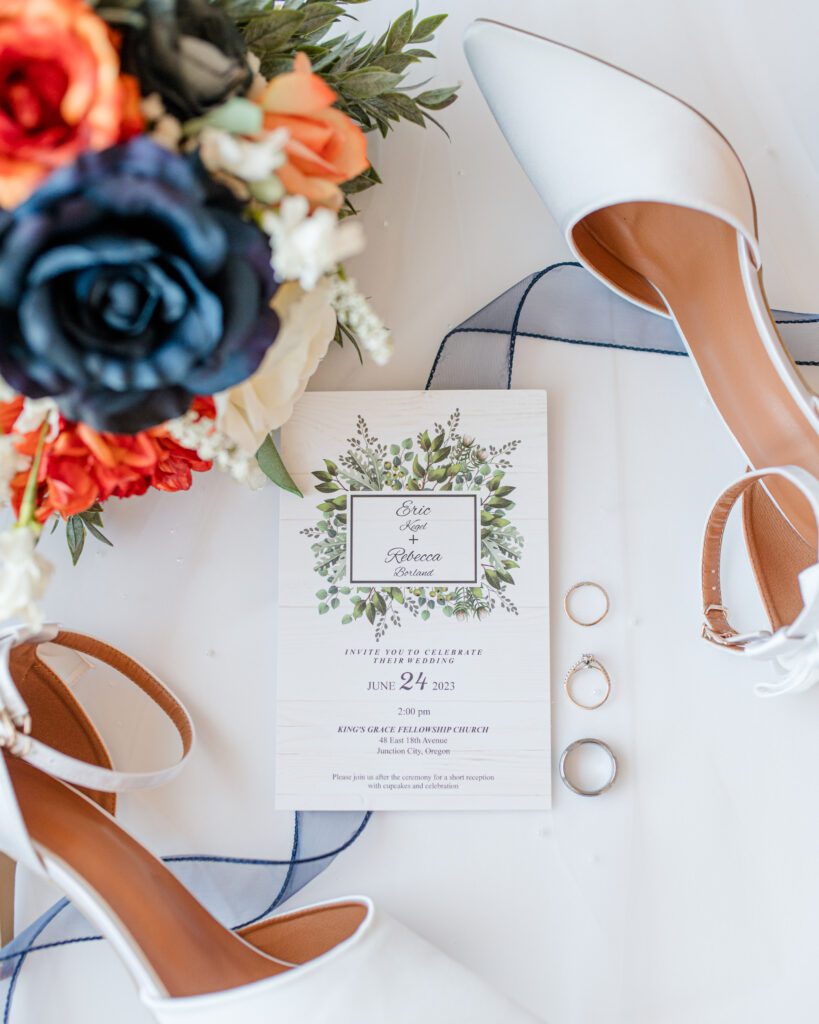 Bridal details of her white heals, flowers, wedding invitation and the wedding rings