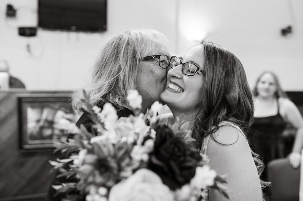 mother of groom kissing on her new daughter-in-law while she is smiling