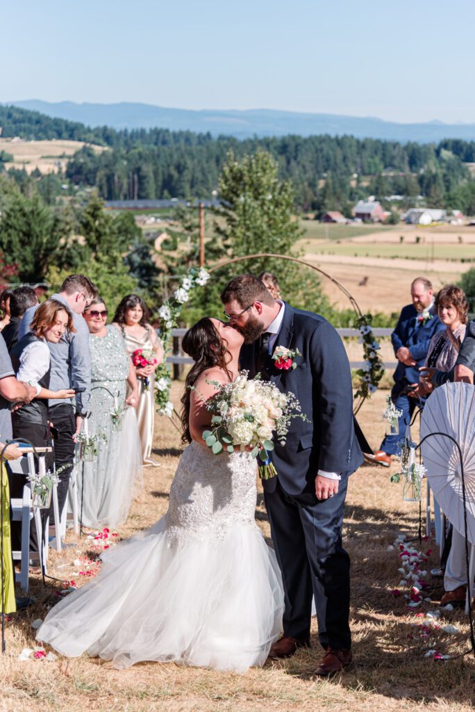 Bride and groom stop for a kiss during their ceremony recession at East Fork Country Estate in Damascus Oregon