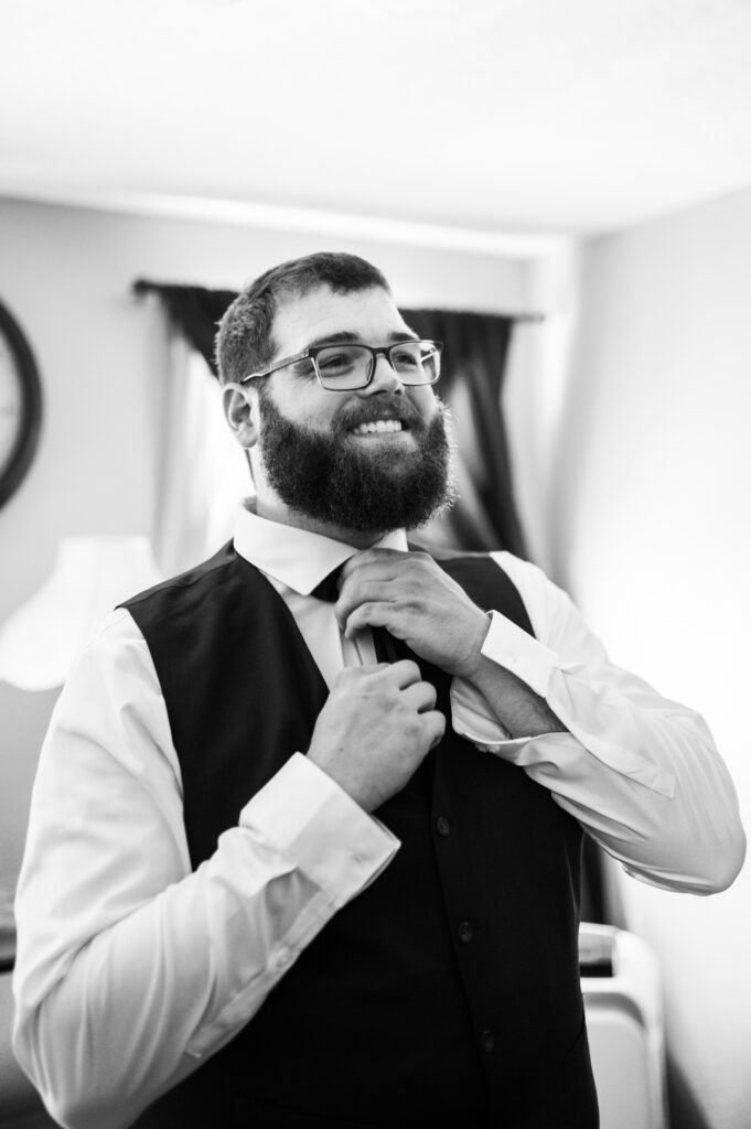 Groom adjusting his tie in the mirror as he prepares for the ceremony at East Fork Country Estate in Damascus Oregon