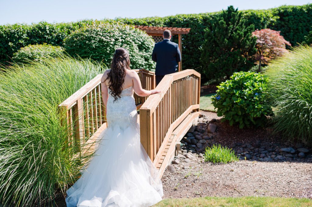 Bride walking up behind her groom on a bridge at their wedding venue at East Fork Country Estate in Damascus Oregon