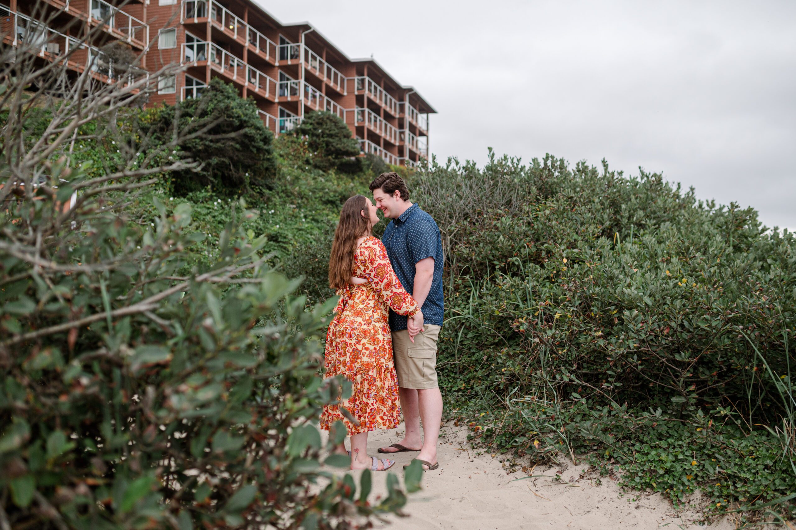 Bride and Groom in bushes at the beach for their engagement session at Cannon Beach