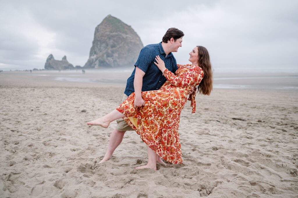 Groom dipping his bride during their engagement session in Cannon Beach Oregon