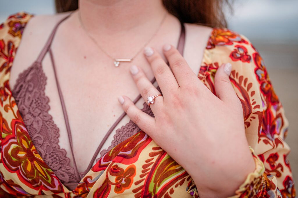 brides hand resting on her chest for a close up of her ring during her engagement session in cannon beach oregon